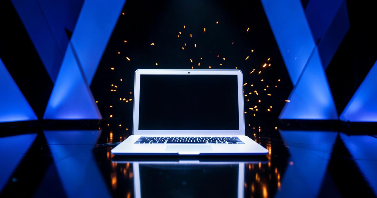 Glowing laptop on a dark stage with blue and orange light